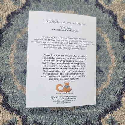 White greeting card with text titled "Divine Goddess of Love and Creation" on a textured blue and gray fabric background.